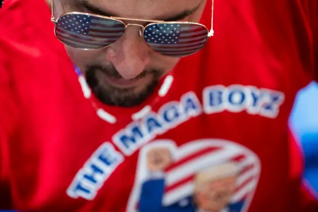Tattooed millennial cryptocurrency investor in a t-shirt "you are boyz" U.S. President Donald Trump speaks during a campaign rally at the Cambria County War Memorial on August 30, 2024 in Johnstown, Pennsylvania. 