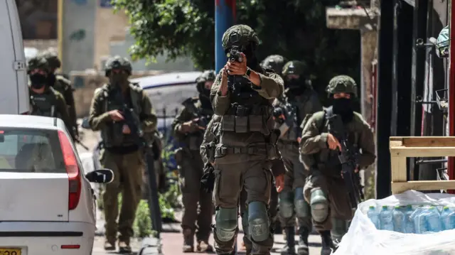 A member of the Israeli security forces points a weapon while patrolling the Qalandiya refugee camp, south of Ramallah, on August 5, 2026.