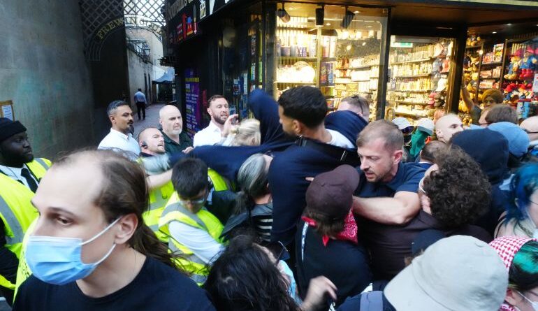OXFORD, ENGLAND - JUNE 17: Security officers stand guard as attendees clash with protesters as they climb barriers as far-right activist Tommy Robinson addresses the Oxford Union at Oxford University on June 17, 2026 in Oxford, England. Far-right activist Tommy Robinson (real name Stephen Yaxley-Lennon) talks about the proposal, "This house believes that the West is right to be suspicious of Islam" in the Oxford Union. Robinson debates with far-right campaigner Laurence Fox and journalist Jonathan Sacerdot. The opposition includes former Conservative MP Jacob Rees-Mogg, activist Abdullah Al Andalus and podcaster Michael Doward. (Photo by Chris Eades/Getty Images)