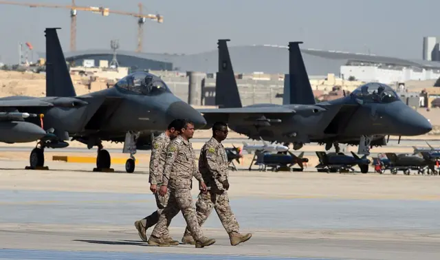 Saudi army officers walk in front of fighter jets "F-15" and bombs "JBU" Missiles are shown during a ceremony marking the 50th anniversary of the King Faisal Air College at King Salman Air Base on January 25, 2017 in Riyadh.